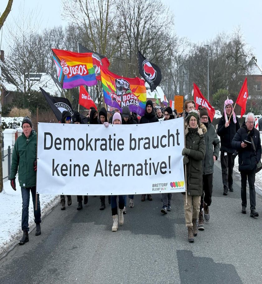 Demonstrationszug mit Regenbogenfahnen und dem Banner „Demokratie braucht keine Alternative“