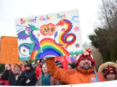 Selbstgemaltes Schild „Brettorf bleibt bunt“ mit zwei bunten Drachen und Regenbogen, hochgehalten bei einer Demonstration
